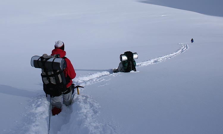 Three explorers trekking through the snow 