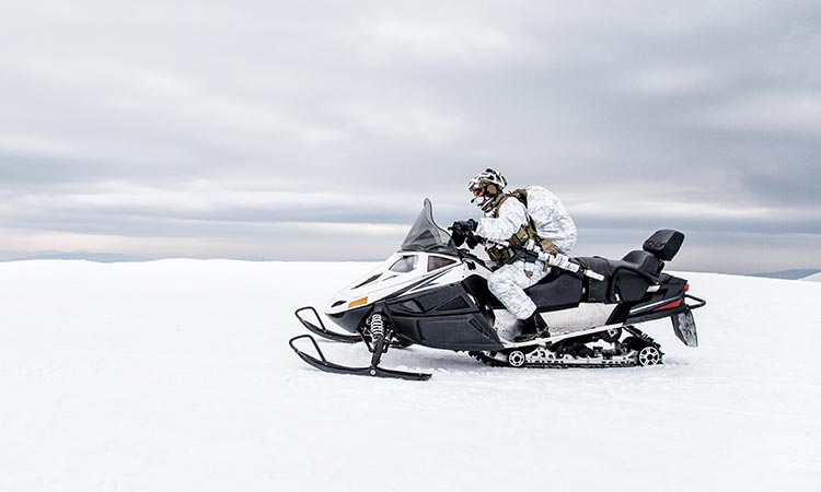 Someone on a snowmobile driving over the snow 