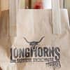 Longhorns branded takeaway bag and coffee cup, with two LNOF staff sat in the background