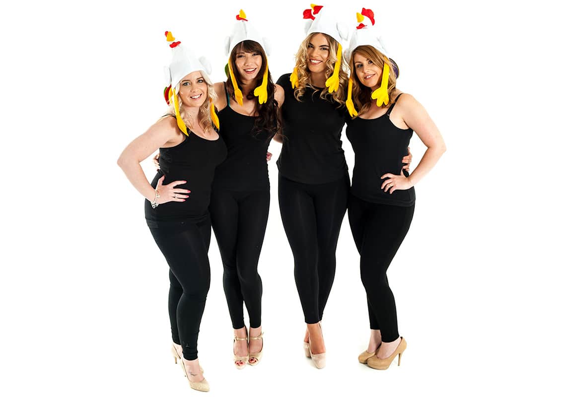 a hen group in black outfits wearing chicken hats