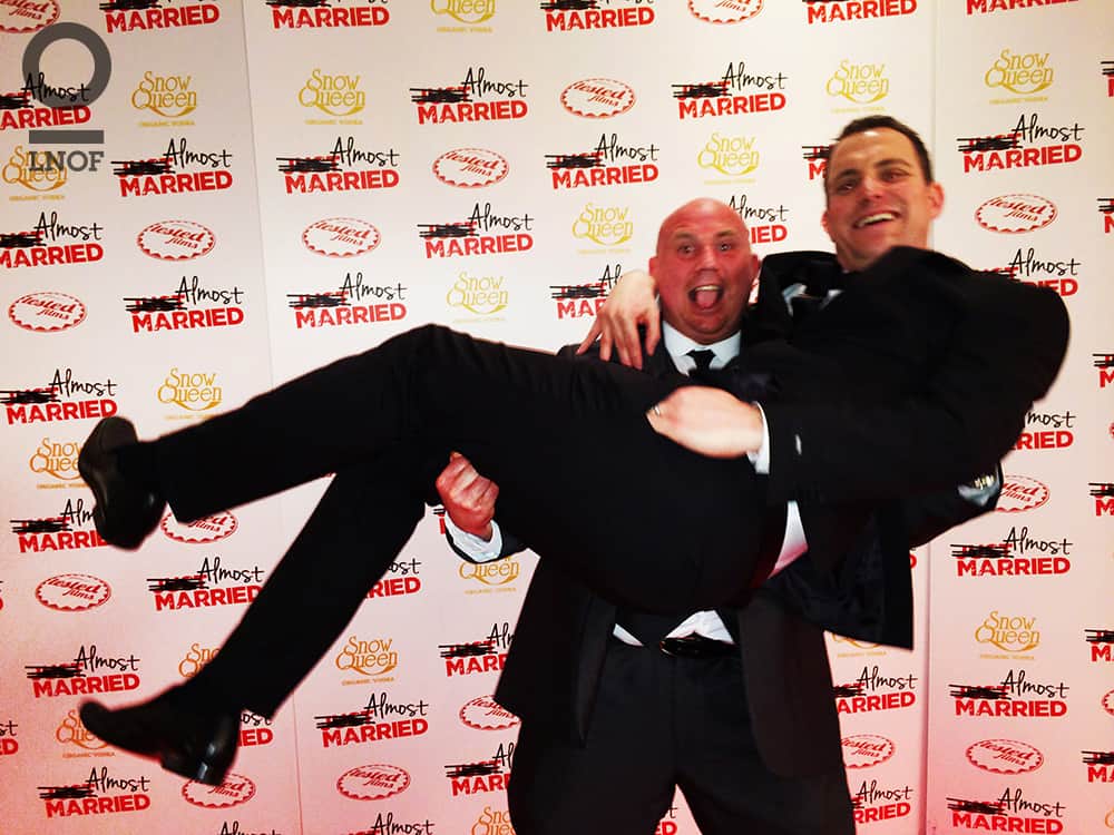 A man in a suit, carrying another man in a suit at the Almost Married film premier
