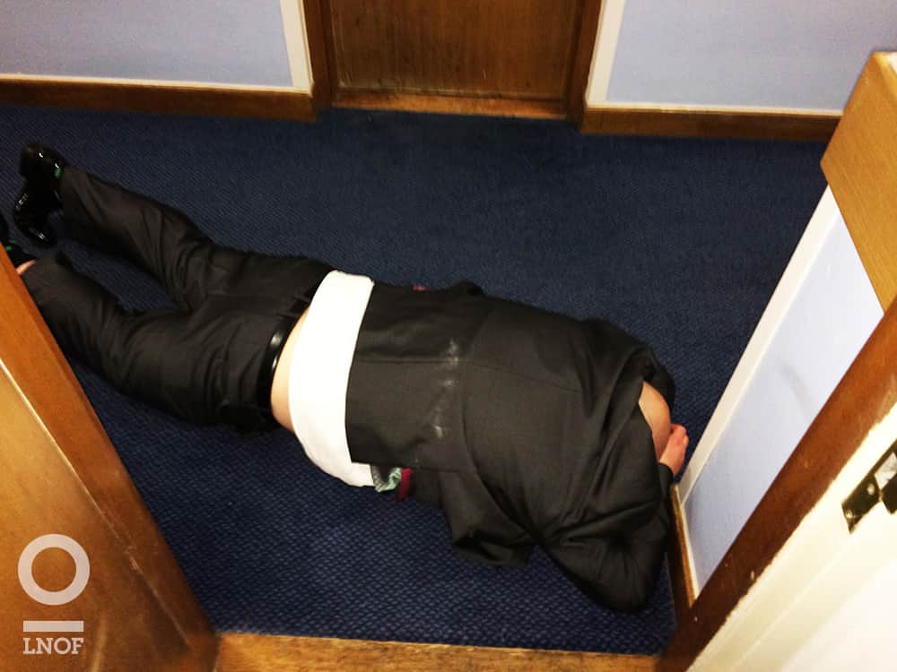 A man in a suit, face down and asleep in a doorway