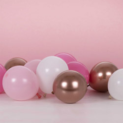 Pink, white, and bronze balloons against a pink backdrop.