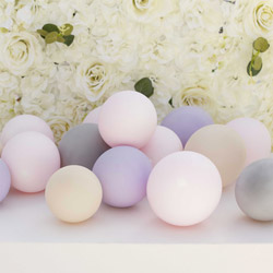 Lilac, pink, white, and grey balloons against a rose wall backdrop.
