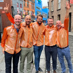 A group of men on a stag do all wearing orange stand out shirts