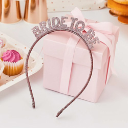 Rose Gold Glitter Bride to Be Headband propped up against a present.
