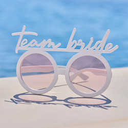 A pair of team bride glasses set beside a pool