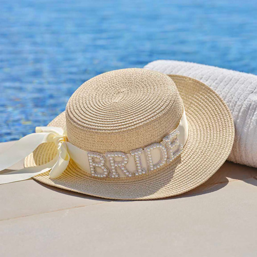 Straw Bride boater hat laying next to a pool.