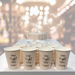 The Hen Party Beer Pong cups and balls set up on on a table with a decorative background.