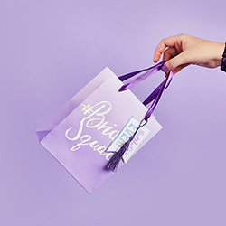 Somebody holding the gift bag by the purple ribbon.