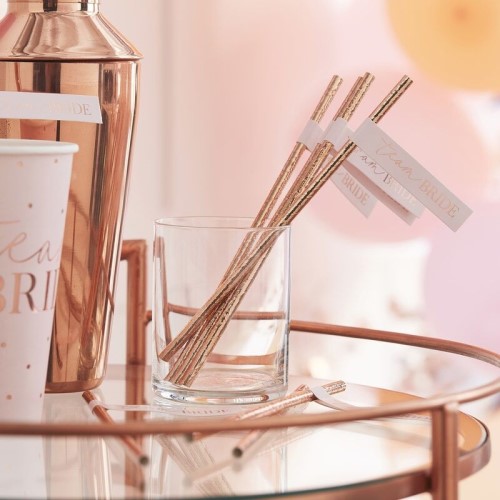 The rose gold straws seen in a glass.