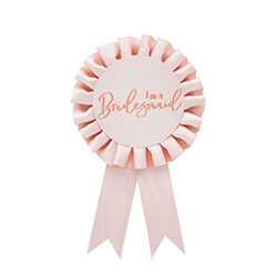 Rose gold bridesmaid rosette badge against a white background.
