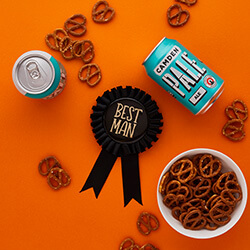 Best man rosette on an orange table with some ale.
