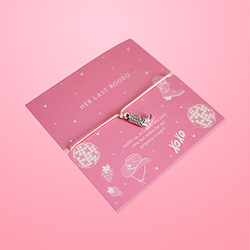 A bracelet with a cowboy boot charm in cute pink packaging. 