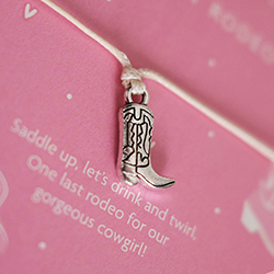 A bracelet with a cowboy boot charm in cute pink packaging. 