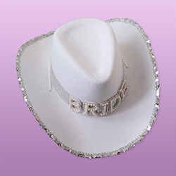 A white cowboy hat that reads 'BRIDE' with a sparkly silver trim. 